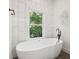 Modern bathroom featuring a standalone tub, black fixtures, and a serene view from the window with white tile at 2423 Melinda Ne Dr, Atlanta, GA 30345