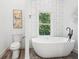 Bathroom featuring a modern standalone tub, toilet, and contemporary artwork for an elegant and relaxing space at 2423 Melinda Ne Dr, Atlanta, GA 30345