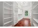 Spacious walk-in closet with custom shelving, drawers, hardwood floors, and recessed lighting for ample storage at 2423 Melinda Ne Dr, Atlanta, GA 30345
