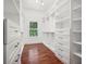 Well-organized walk-in closet featuring custom white shelving, built-in drawers, and gleaming hardwood flooring at 2423 Melinda Ne Dr, Atlanta, GA 30345