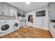 Well-organized laundry room featuring wooden floors, white cabinets, and modern appliances at 4770 Hilltop Nw Dr, Acworth, GA 30101