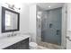 Modern bathroom featuring a glass enclosed shower with gray tile, pebble flooring, marble accents, and dark vanity at 2288 Street Deville Ne, Atlanta, GA 30345