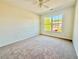 Well-lit bedroom with neutral carpet, ceiling fan, and a view of the neighborhood at 5819 Rue Chase Way, Tucker, GA 30084