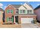 Two-story brick home featuring green shutters, a white garage door, and manicured landscaping at 5819 Rue Chase Way, Tucker, GA 30084