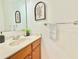 Neutral half bathroom with wood vanity, bright counter, and decorative leafy art piece at 5819 Rue Chase Way, Tucker, GA 30084
