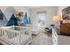 A Bedroom featuring a modern mountain themed accent wall, with two cribs, a rocking chair, and decor at 146 Silver Leaf Trce, Douglasville, GA 30134