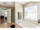 Bright bathroom showcasing a soaking tub with a decorative window and adjacent glass enclosed shower at 4048 Sandy Branch Ne Dr, Buford, GA 30519