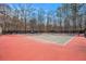 Community tennis court with red and green surface surrounded by trees at 4283 Brighton Nw Way, Kennesaw, GA 30144