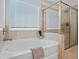 Bright bathroom with bathtub and glass-enclosed shower with light tile at 66 Snowdon Way, Villa Rica, GA 30180