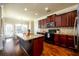 Well-lit kitchen with granite countertops, dark wood cabinets, stainless steel appliances, and wood floors at 2401 Day Break Way, Dacula, GA 30019