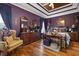 Elegant bedroom featuring dark purple walls, hardwood floors, tray ceiling, and refined decor at 5034 Kingsbridge Pass, Powder Springs, GA 30127