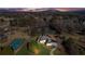 Expansive estate featuring a tennis court, water feature, and mountain view, set amidst lush greenery under a colorful sunset sky at 5690 Rutland Trce, Lithonia, GA 30058