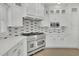 Close up of stainless steel stove with white cabinets and modern backsplash at 5690 Rutland Trce, Lithonia, GA 30058
