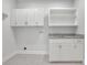 Well-lit laundry room with gray countertops, white cabinets and open shelving at 5690 Rutland Trce, Lithonia, GA 30058