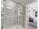 Modern tiled shower with glass door and built-in niche, adjacent to a view of the bright main bedroom at 5833 Schelton Se Pl, Mableton, GA 30126