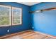 An empty bedroom with a blue accent wall and two bright windows at 703 Somerset Dr, Lawrenceville, GA 30046