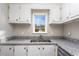 Close-up of kitchen featuring stainless steel sink, window, white cabinets and granite countertops at 2370 Mcafee Rd, Decatur, GA 30032