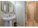 Elegant powder room features a pedestal sink and decorative mirror, complemented by warm neutral tones at 4780 Woodruff Trce, Cumming, GA 30028