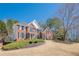 Brick home with a well-maintained lawn and landscaping, featuring classic architecture under a clear blue sky at 4780 Woodruff Trce, Cumming, GA 30028