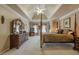 Spacious bedroom with a four-poster bed, tray ceilings, neutral carpet, and a decorative ceiling fan at 4780 Woodruff Trce, Cumming, GA 30028