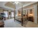 This main bedroom features a four-poster bed, tray ceilings, decorative columns, and carpeted floors at 4780 Woodruff Trce, Cumming, GA 30028