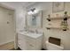 Bright bathroom featuring a white vanity with marble countertop, decorative mirror, and floating shelves at 3280 Spincaster Way, Loganville, GA 30052