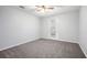 A cozy bedroom with light-colored walls, gray carpet, ceiling fan, and a door to a balcony at 1510 Gettysburg Pl, Atlanta, GA 30350