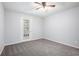 A cozy bedroom with light-colored walls, gray carpet, ceiling fan, and a door to a balcony at 1510 Gettysburg Pl, Atlanta, GA 30350