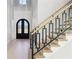 Hallway with staircase leading to upper floors, featuring modern railing, arched front doors, and light floors at 3057 Bold Springs Rd, Dacula, GA 30019