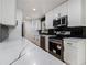 Modern kitchen boasts white countertops, white cabinets, stainless appliances and black subway tile at 546 Milligan Dr, Stone Mountain, GA 30083