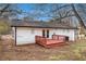 Back of house with small wooden deck and white painted siding and a partially bare backyard at 7437 Nulan Way, Riverdale, GA 30274