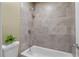 Tiled bathroom shower with neutral gray tile, white tub, and brushed metal fixtures at 80 Montre Nw Sq, Atlanta, GA 30327