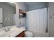 Bathroom vanity with double sinks, tub/shower combo with white shower curtain, and a wall shelf for storage at 2480 Copper Mill Trl, Cumming, GA 30041