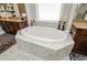 Bathroom showcasing a marble tub and adjacent vanity, illuminated by natural light from a window at 2480 Copper Mill Trl, Cumming, GA 30041