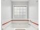 Soaking tub with window, white tile and horizontal red accent stripe at 848 Gateshead Ct, Lawrenceville, GA 30043