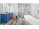 Chic bathroom featuring a soaking tub, a glass shower, and a vanity with blue cabinets at 3280 Stillhouse Se Ln # 101, Atlanta, GA 30339