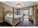 Sunlit bedroom with a four-poster bed, hardwood floors, and access to a private balcony at 3280 Stillhouse Se Ln # 101, Atlanta, GA 30339