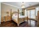 Spacious bedroom featuring a four-poster bed, hardwood floors, and access to a private balcony at 3280 Stillhouse Se Ln # 101, Atlanta, GA 30339