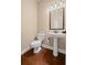 Elegant powder room with pedestal sink, stylish mirror, and hardwood floors at 4930 Cecilia Sq, Cumming, GA 30040