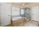 Bathroom with soaking tub, glass-enclosed shower, and decorative window at 4930 Cecilia Sq, Cumming, GA 30040