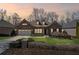 Dusk view of a charming brick home with well-manicured lawn, complimented by a two-car garage and mature trees at 4930 Cecilia Sq, Cumming, GA 30040