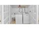 Bright laundry room featuring sink, washer, and dryer behind french doors at 303 Fireside Trl, Douglasville, GA 30134