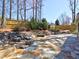 Scenic backyard with stacked rock water feature, stone patio, and wooded landscape at 3304 Woolbridge Ct, Marietta, GA 30062