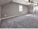 A spacious bedroom featuring plush gray carpeting, a ceiling fan, and ample natural light from the windows at 410 Invector Ct, Locust Grove, GA 30248