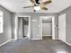 A bright bedroom with gray walls, ceiling fan and plush carpet features access to closets and storage areas at 410 Invector Ct, Locust Grove, GA 30248