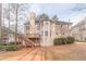 Back exterior view of a multi-story tan home with a deck, stairs, and landscaped yard at 1351 Mckendree Park Ct, Lawrenceville, GA 30043