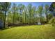 Expansive backyard featuring lush green grass, mature trees, and a charming shed, offering a serene outdoor retreat at 5570 Rolling Oaks Dr, Cumming, GA 30040