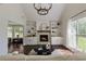 Bright living room features a stone fireplace, built-in shelving, dark hardwood floors and a modern chandelier at 5570 Rolling Oaks Dr, Cumming, GA 30040