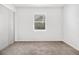 Bright bedroom with neutral carpet, white walls, and a window providing natural light at 6615 Buckhurst Trl, Atlanta, GA 30349