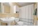 Bathroom with a white pedestal sink, toilet, cabinet, shower with a striped curtain, and gold hardware at 4460 Wimberly Way, Cumming, GA 30028